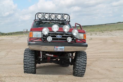 1990 Ford Bronco - This modified Ford truck sits high on large tires, equipped for off-road adventures with numerous lights.