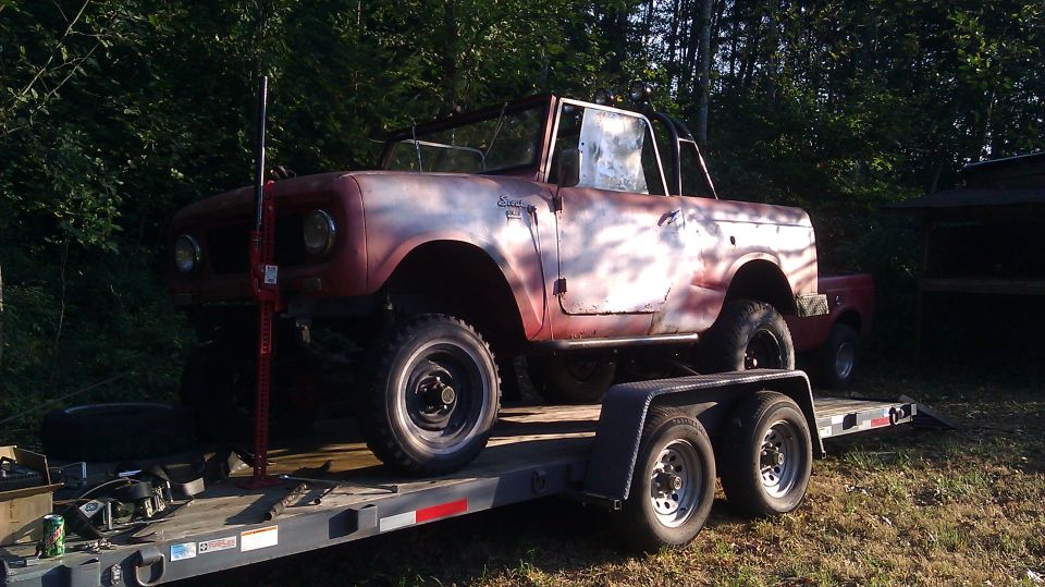 Red International Scout on a trailer, with a Hi-Lift jack mounted on the front