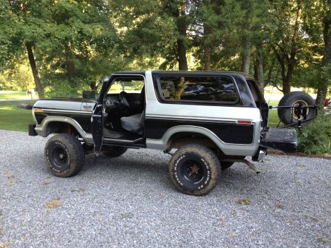 1979 Ford Bronco - This two-tone Ford Bronco is parked on a gravel driveway with trees in the background.