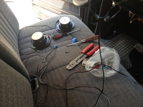1979 Ford Bronco - Tools and speakers are laid out on the fabric seat of a vehicle, suggesting an ongoing installation or repair.