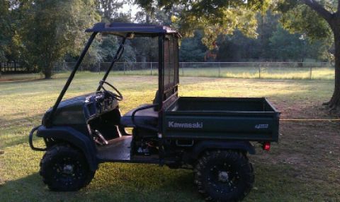 1989 Ford Bronco - A green Kawasaki Mule utility vehicle is parked outdoors on a grassy area.