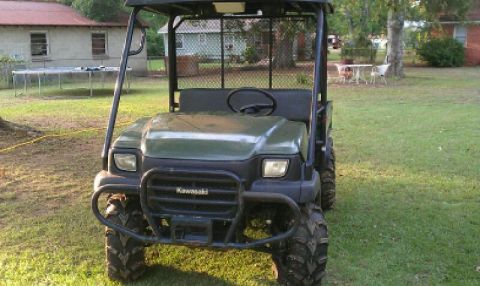 1989 Ford Bronco - Front view of a Kawasaki utility vehicle with large tires, parked outdoors.