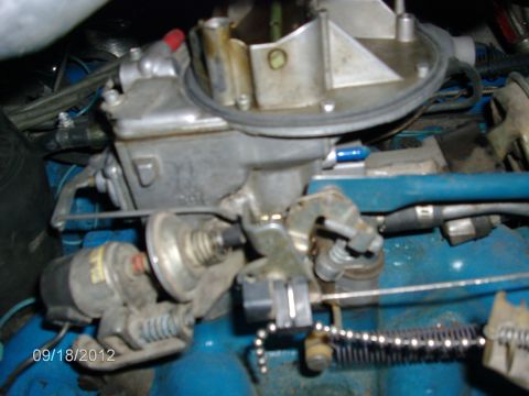 1979 Ford F-150 - A detailed view of a carburetor assembly, highlighting mechanical linkages and blue-painted engine parts.