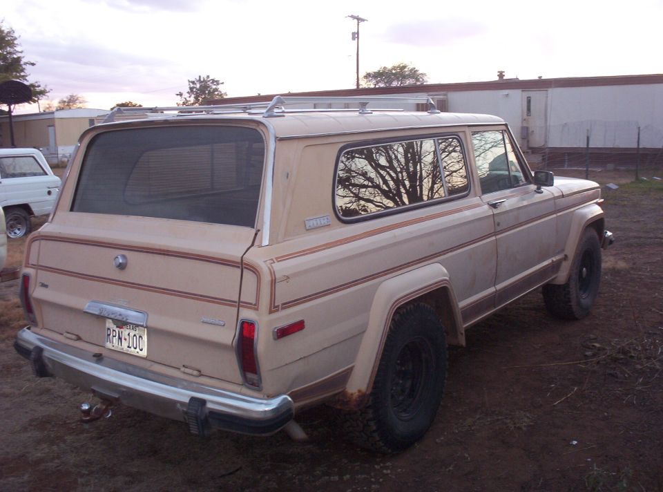 Tan two-door Jeep Cherokee wagon from the rear three-quarter with roof rack and Texas plate