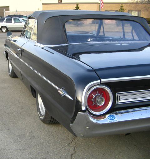 1964 Ford Galaxie - Rear view of a black 1964 Ford Galaxie convertible, showing its distinctive taillight and chrome bumper.