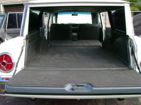 1965 Ford Falcon - The rear cargo area of a 1965 Ford Falcon station wagon is visible, showing the folded-down rear seats and carpeted floor.