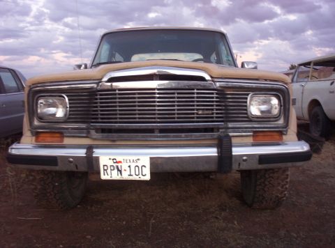 1988 Ford Bronco - Front view of a Jeep Wagoneer, showing its grille and headlights. A second vehicle is visible on the right.