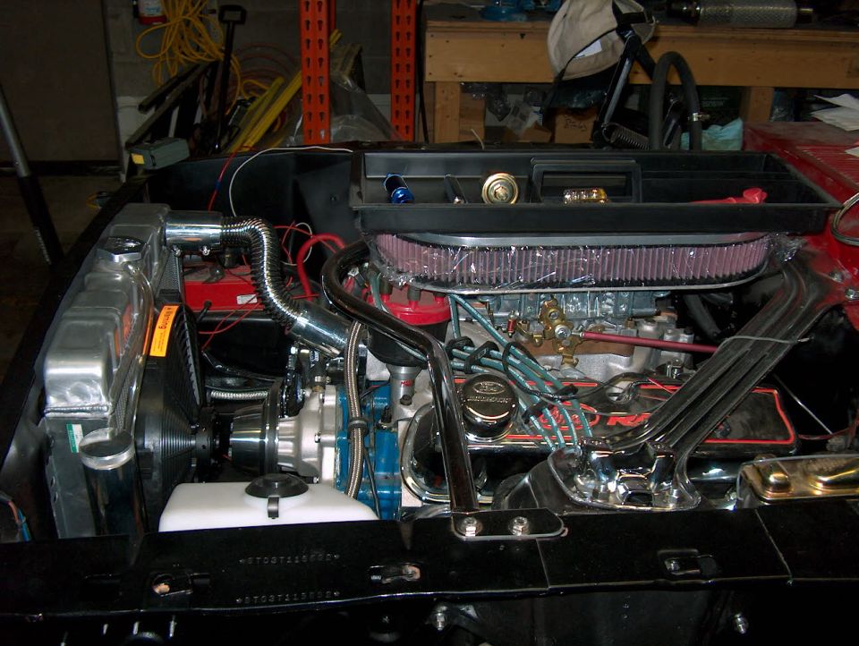 Ford V8 with oval air cleaner and chrome valve covers in a car under restoration