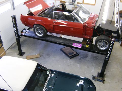 1968 Shelby GT350 - A red convertible is elevated on a car lift, with its hood and trunk open, revealing the interior and engine.