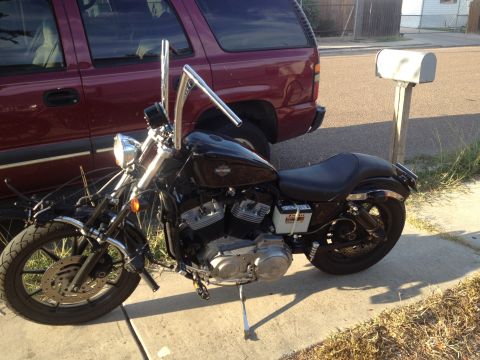 1995 Ford Bronco - A black Harley-Davidson motorcycle is parked on a sidewalk next to a maroon SUV and a mailbox.