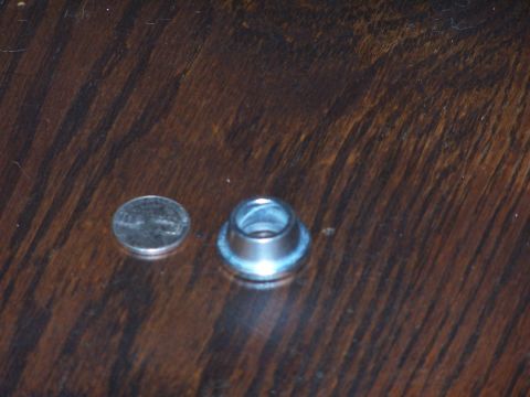 1973 Ford Bronco - A metal grommet and a penny are shown on a wooden table.