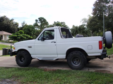 1995 Ford Bronco - White 1995 Ford Bronco parked on a driveway with a spare tire mounted on the rear.