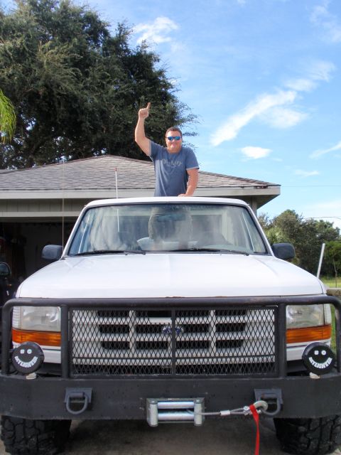 1995 Ford Bronco - A man stands atop a white 1995 Ford Bronco, pointing upwards.