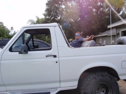 1995 Ford Bronco - Man relaxes in the open-top 1995 Ford Bronco, enjoying the ride.