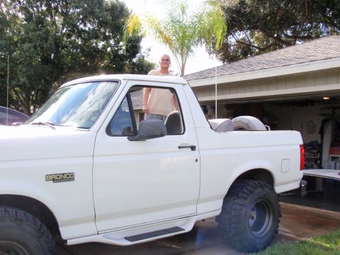 1995 Ford Bronco - A white Ford Bronco is parked in a driveway with a man standing in the open driver's door.