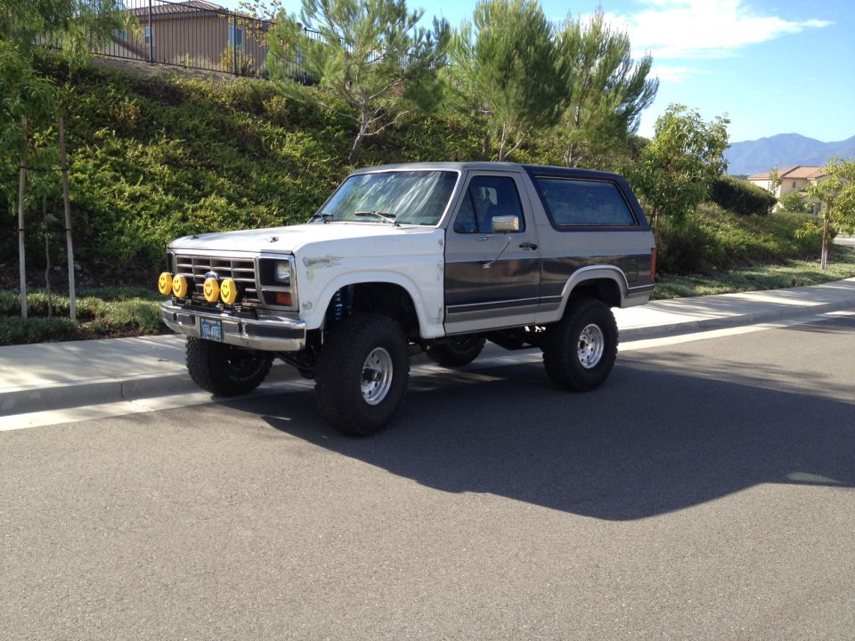 1986 Ford Bronco, lifted, white and grey two-tone, with four yellow fog lights on the front bumper
