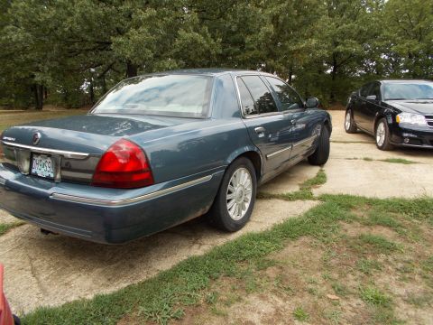 2009 Mercury Grand Marquis - Two sedans parked outdoors on a concrete surface with trees in the background.