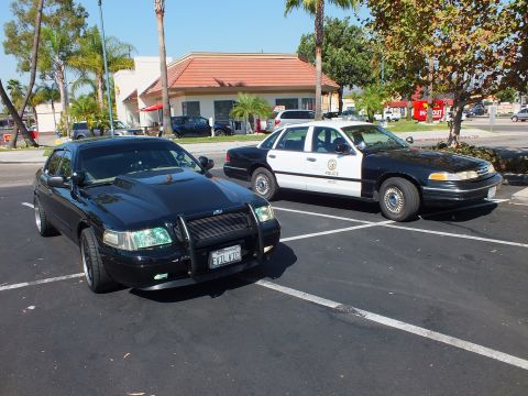 2003 Ford Crown Victoria - Murdered-out sedan with brush guard parked next to a marked LAPD Ford Crown Victoria cruiser.