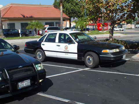 2003 Ford Crown Victoria - Marked LAPD Crown Victoria cruiser in a lot next to a blacked-out sedan with EVIL VIC plate.