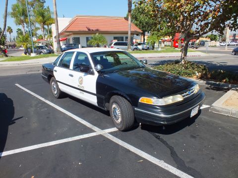 2003 Ford Crown Victoria - Three-quarter view of a marked LAPD Ford Crown Victoria sedan in an empty parking lot.