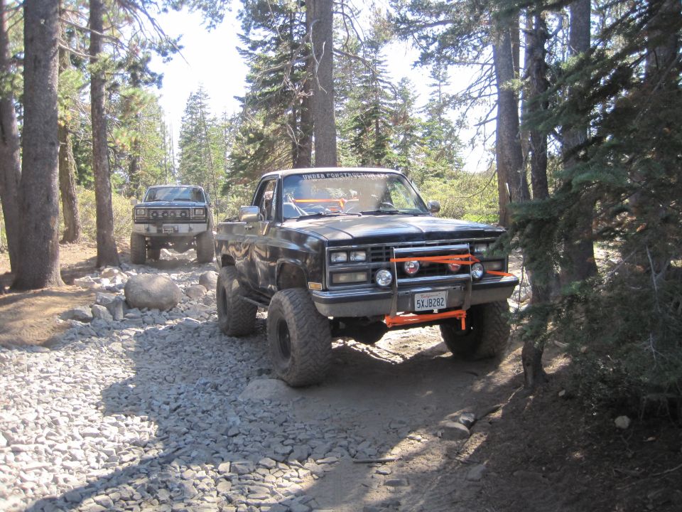 Black pickup truck with orange off-road lights and bumper on a rocky trail
