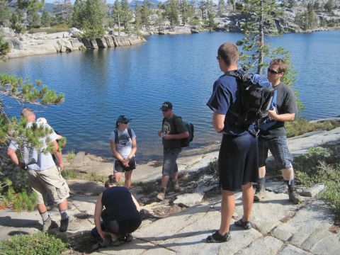 1989 Ford Bronco - A group of hikers pauses by a tranquil lake on a sunny day.