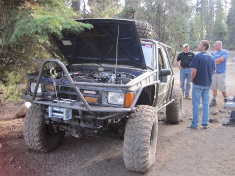 1989 Ford Bronco - Modified Toyota 4Runner with extensive off-road upgrades, hood open, parked outdoors with several people observing.