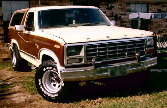 Ford Bronco with wood paneling, front end visible, parked outside a brick house
