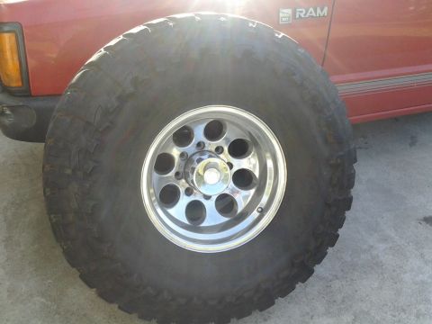 1968 Ford Bronco - Oversized off-road tire and chrome wheel mounted on a red Dodge Ram truck.