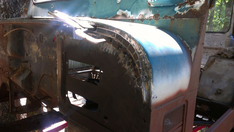 Close-up of rusty, partially disassembled vehicle body, showing exposed metal and blue paint
