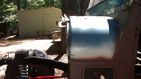 1978 Ford Bronco - A side view of a 1978 Ford Bronco shows its fender and door, with visible rust and a two-tone paint job.