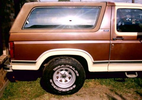 1980 Ford Bronco - Side profile of a brown and white 1980 Ford Bronco XLT showing its body lines and wheels.