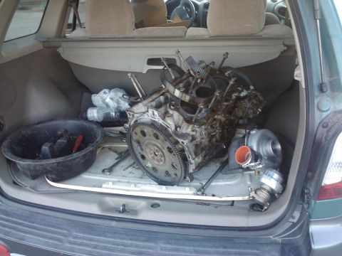 1995 Ford Probe - Engine and turbocharger components are stored in the trunk of a vehicle.