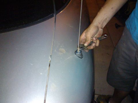 1995 Ford Probe - Someone is working on a car antenna, using a wrench to secure it to the fender.