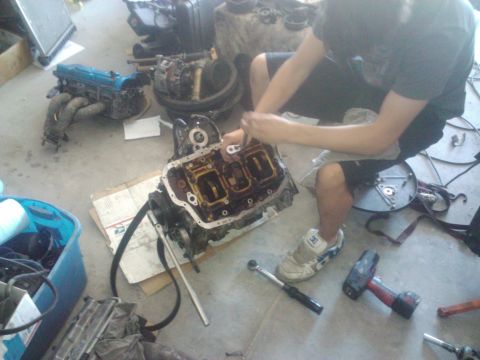1995 Ford Probe - A person works on an engine block with various tools scattered around the workspace.