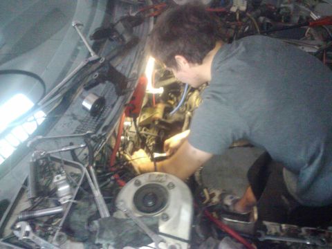 1995 Ford Probe - A person is working on the engine of a car, with many wires and mechanical components visible.