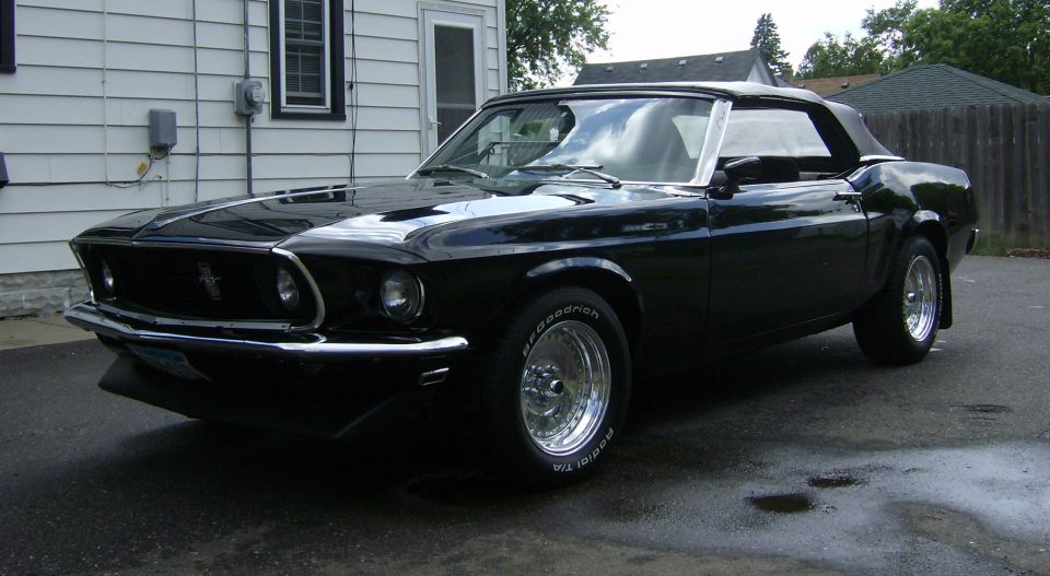 Black 1969 Ford Mustang convertible parked in driveway