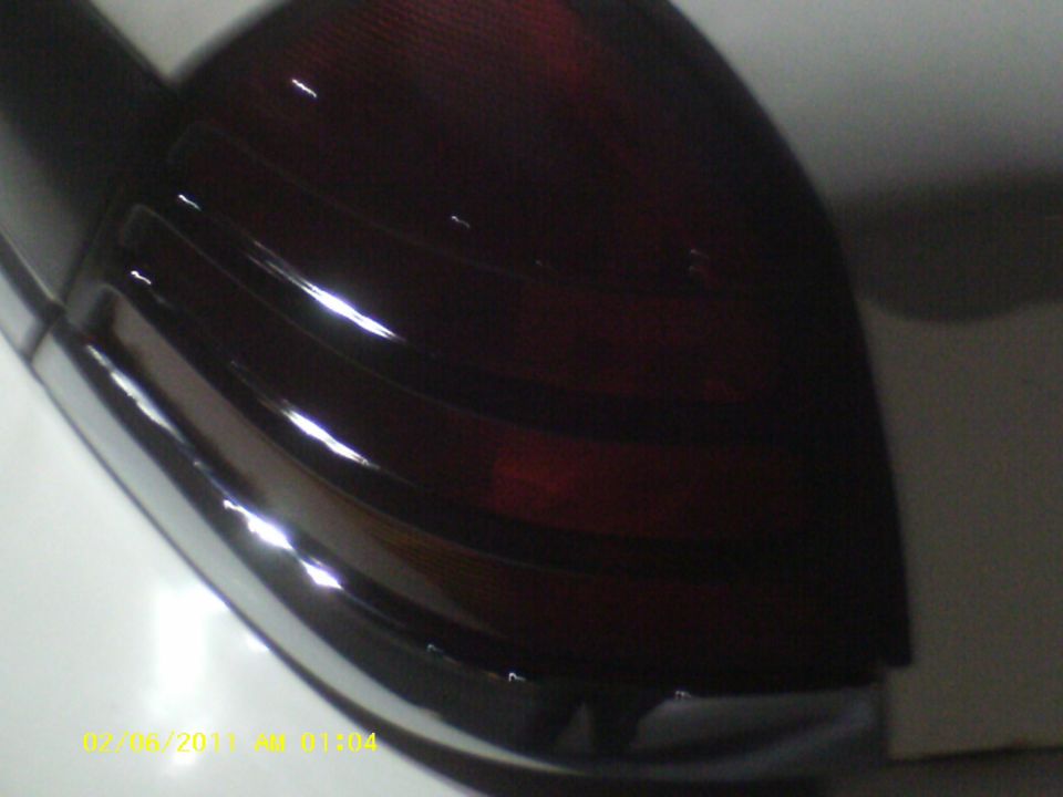 Close-up of a dark red vehicle taillight with chrome trim