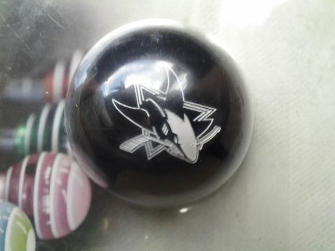 1968 Ford Bronco - A black shift knob the San Jose Sharks logo is shown, with other shift knobs visible in the background.