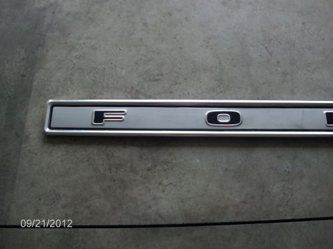 1979 Ford F-150 - A Ford emblem trim piece is shown against a gray concrete background.