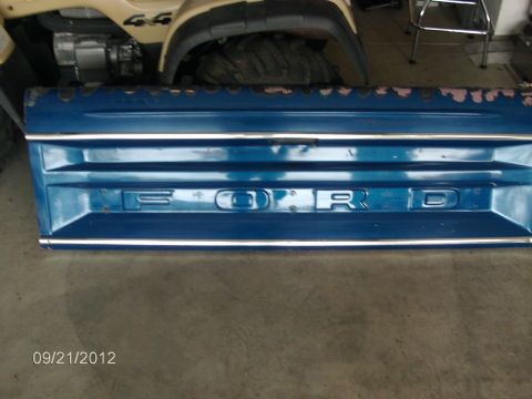 1979 Ford F-150 - A blue Ford tailgate is shown with chrome trim and raised lettering spelling out 'FORD'.