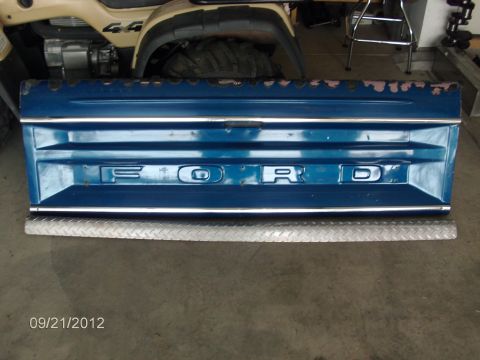 1979 Ford F-150 - A blue Ford tailgate is shown with chrome trim and a diamond plate bumper guard.