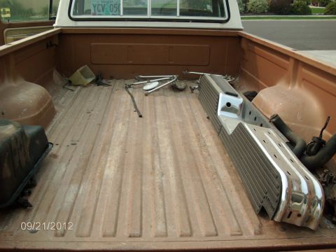 1979 Ford F-150 - The bed of a 1979 Ford F-150 pickup truck contains a chrome bumper and other disassembled parts.