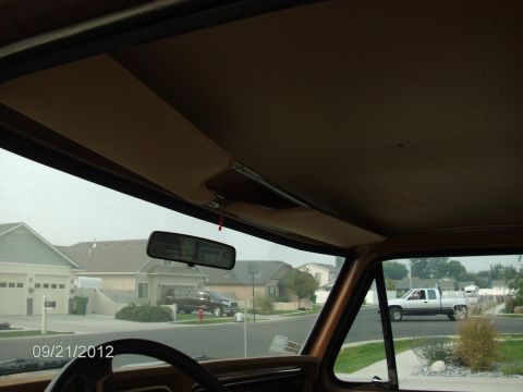 1979 Ford F-150 - Looking out from the cab of a truck at a residential street with another truck passing by.