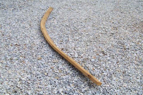 1994 Ford F-150 - A curved wooden trim piece lies on a bed of gravel, with a SuperMotors logo visible in the lower right corner.
