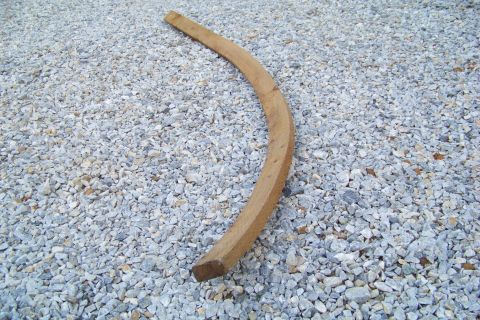 1994 Ford F-150 - A curved wooden piece rests on a surface covered in small, light-colored stones. A website watermark is visible in the lower right corner.
