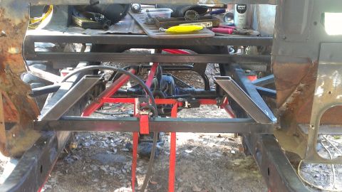 1978 Ford Bronco - The underside of a vehicle is shown with suspension parts and tools laid out on a makeshift workbench.