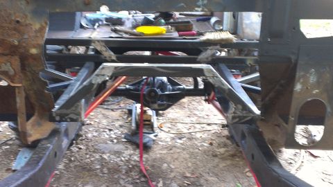 1978 Ford Bronco - The underside of a vehicle undergoing repair, showing the frame and rear axle assembly.