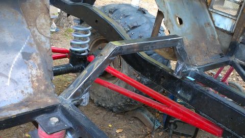1978 Ford Bronco - Close-up view of a custom off-road vehicle's frame, red suspension components and a large tire. The Supermotors.net logo is visible in the…