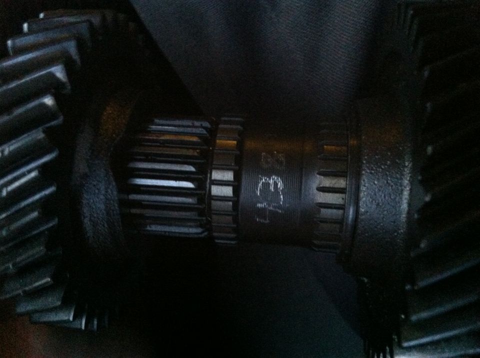 Close-up of two dark metal gears, one with visible splines and stamped numbers '43 E7'